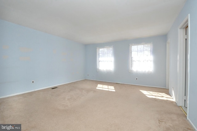 spare room with baseboards, visible vents, and light colored carpet