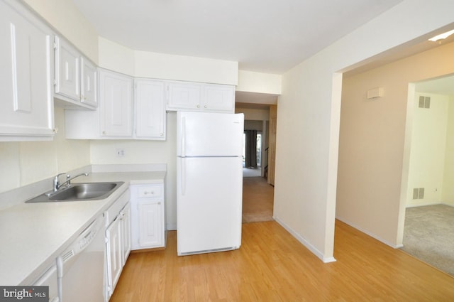 kitchen with white appliances, white cabinetry, light countertops, and a sink