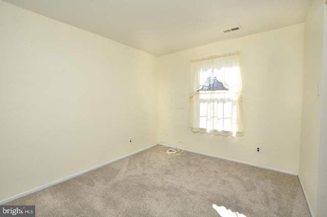 spare room featuring carpet flooring, visible vents, and baseboards