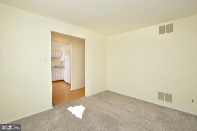 empty room with light carpet, visible vents, and baseboards