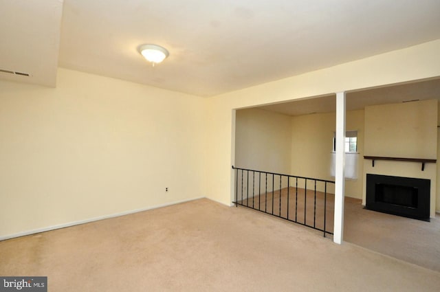 carpeted spare room featuring a fireplace with flush hearth