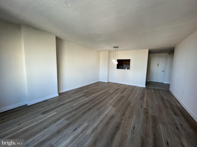 interior space featuring dark wood finished floors, a textured ceiling, and baseboards