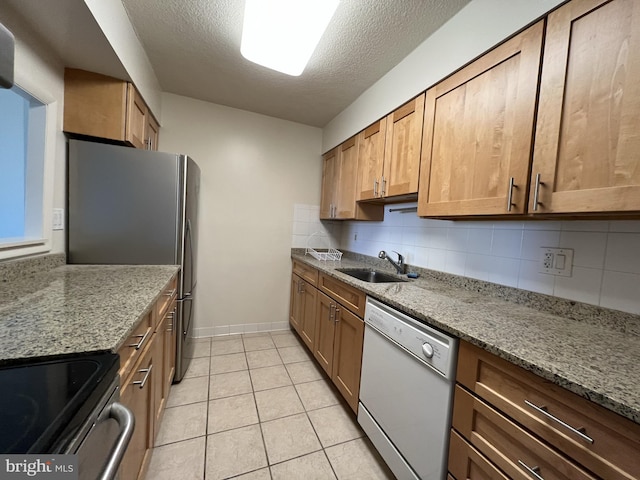 kitchen featuring light stone counters, backsplash, white dishwasher, and a sink