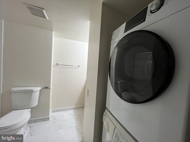 laundry area with laundry area, baseboards, visible vents, stacked washer / drying machine, and marble finish floor