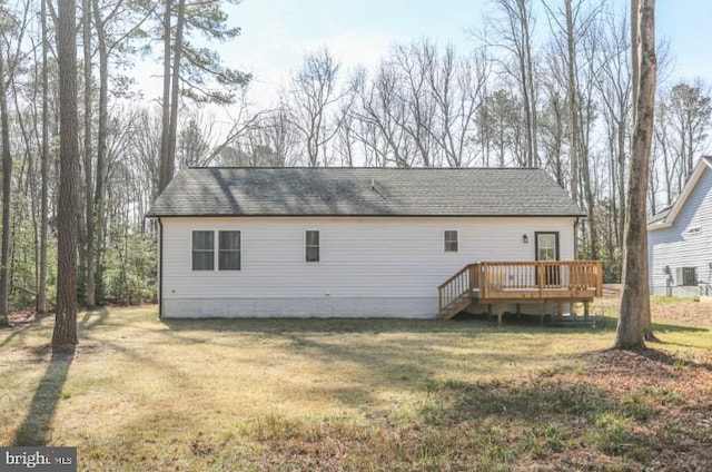 rear view of house with a shingled roof, a yard, and a deck