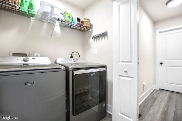 laundry room with washer and clothes dryer, wood finished floors, and baseboards