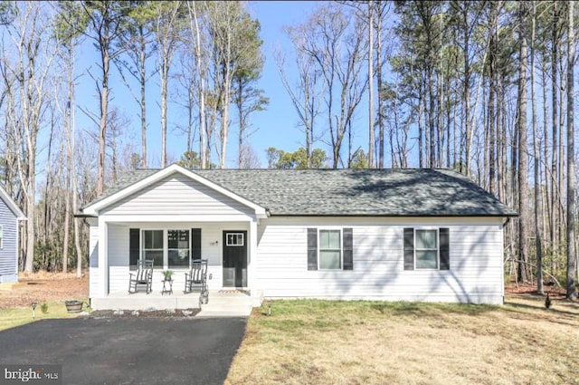 ranch-style home with a front yard, covered porch, and driveway