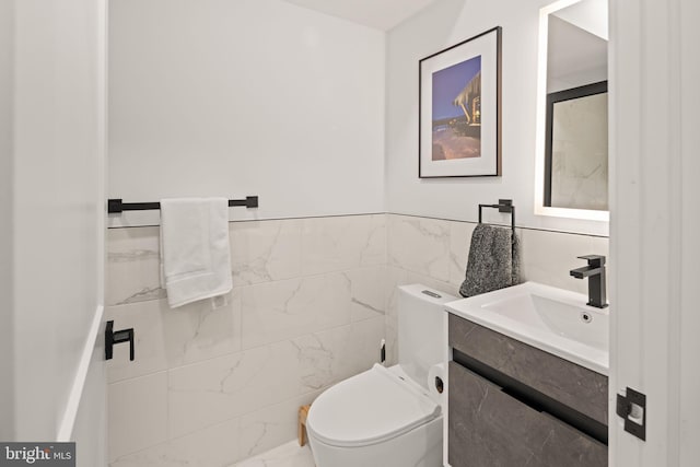 half bathroom featuring toilet, tile walls, and vanity