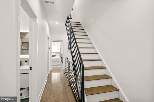 stairway with recessed lighting, visible vents, baseboards, and wood finished floors