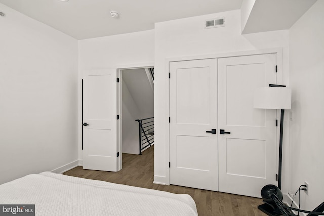 bedroom featuring visible vents, baseboards, a closet, and wood finished floors