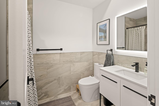 bathroom with vanity, a shower with shower curtain, a wainscoted wall, tile walls, and toilet