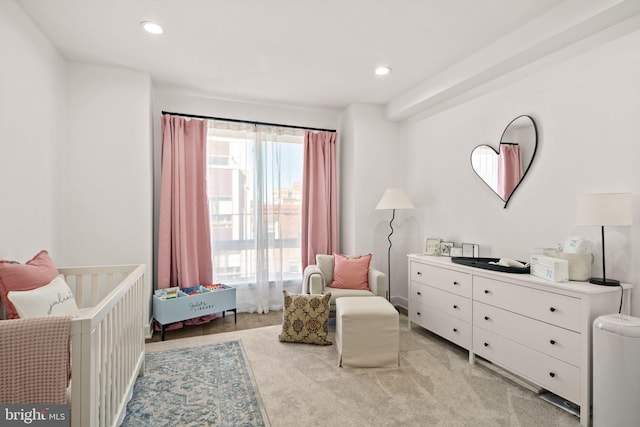 bedroom featuring light carpet, recessed lighting, and a crib