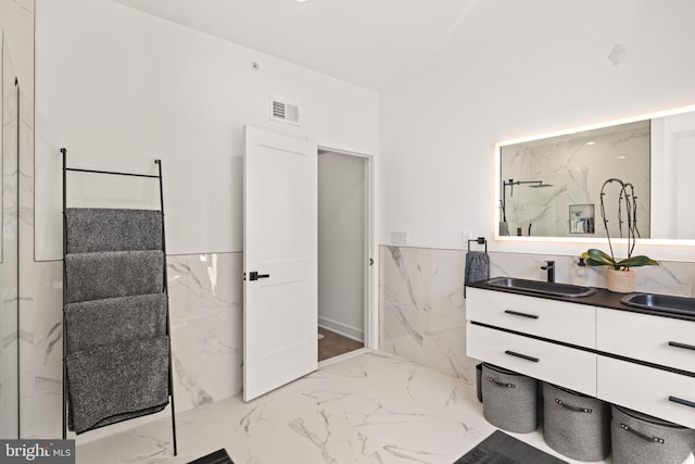 full bathroom featuring visible vents, marble finish floor, tile walls, wainscoting, and vanity