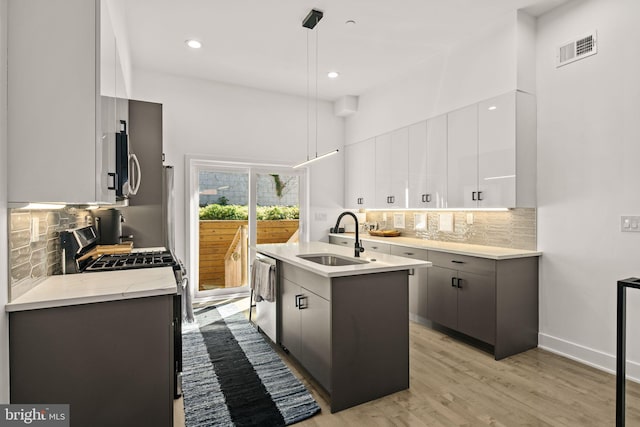 kitchen with visible vents, a kitchen island with sink, stainless steel appliances, a sink, and modern cabinets