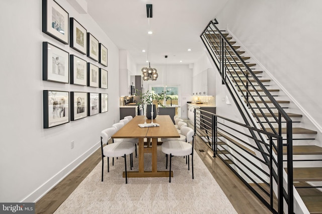 dining room featuring baseboards, an inviting chandelier, recessed lighting, dark wood-style flooring, and stairs