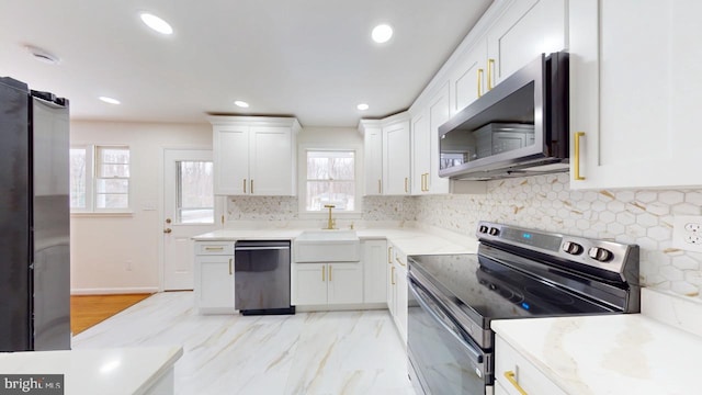 kitchen featuring a sink, backsplash, recessed lighting, stainless steel appliances, and white cabinets