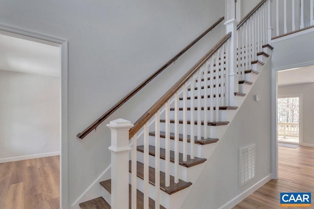 stairway with wood finished floors, visible vents, and baseboards