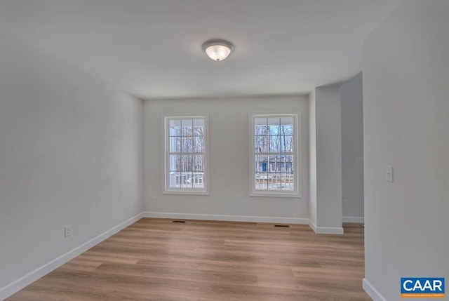 unfurnished room with baseboards, visible vents, and light wood finished floors