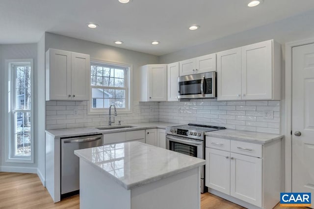 kitchen featuring stainless steel appliances, a center island, white cabinetry, and a sink