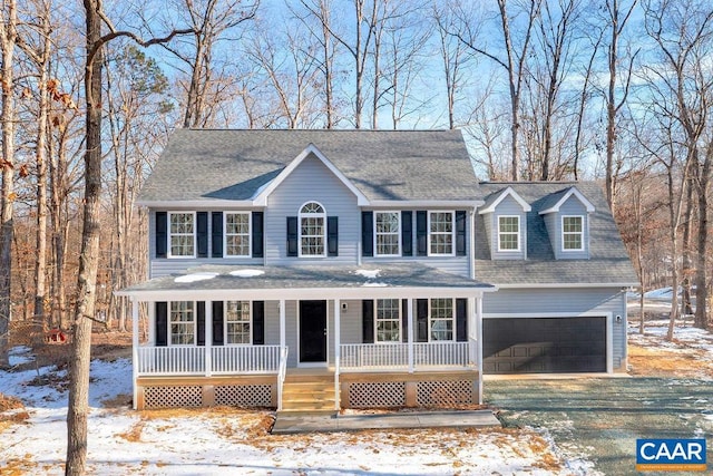 colonial inspired home with a garage, a porch, and a shingled roof