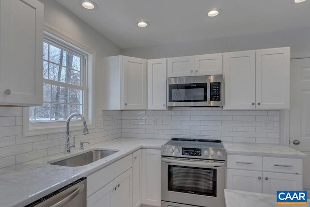 kitchen featuring stainless steel appliances, a sink, white cabinetry, and decorative backsplash