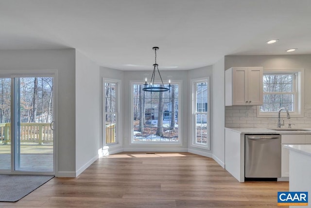 unfurnished dining area with a chandelier, recessed lighting, a sink, baseboards, and light wood-style floors