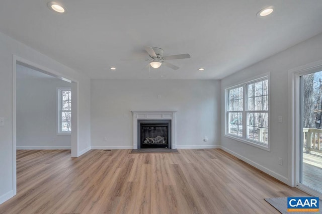 unfurnished living room with a fireplace with flush hearth, recessed lighting, and a healthy amount of sunlight