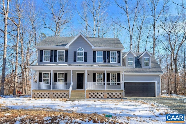 colonial inspired home featuring an attached garage, covered porch, and aphalt driveway