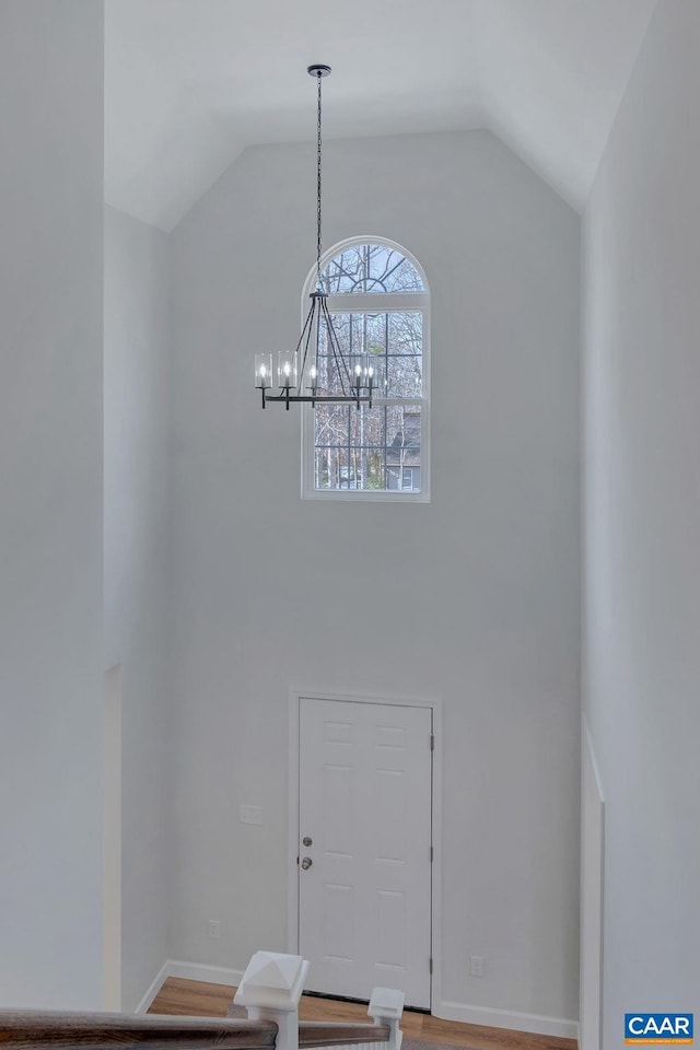 interior space featuring baseboards, high vaulted ceiling, wood finished floors, and an inviting chandelier