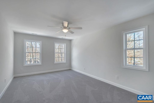 spare room featuring visible vents, dark colored carpet, a ceiling fan, and baseboards