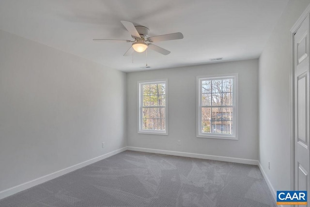 carpeted empty room with visible vents, ceiling fan, and baseboards