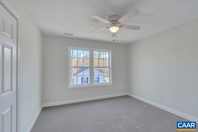 empty room with carpet floors, visible vents, baseboards, and a ceiling fan