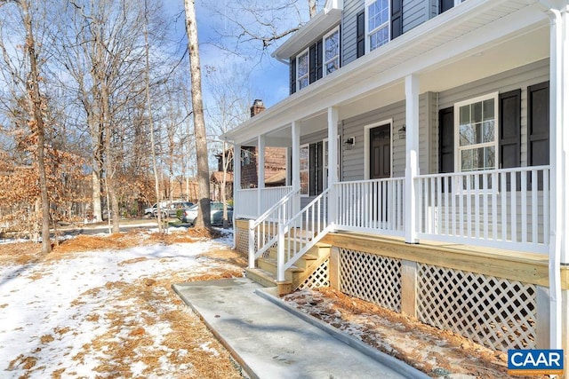 snow covered property entrance with covered porch