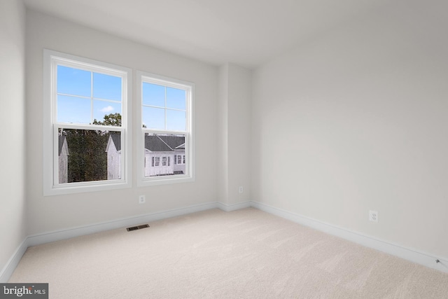 empty room featuring carpet floors, baseboards, and visible vents