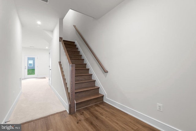 staircase with baseboards, wood finished floors, and recessed lighting