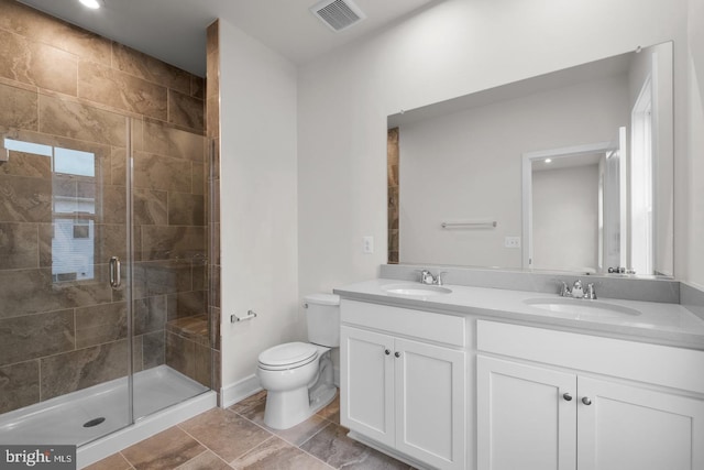 full bathroom with toilet, a sink, visible vents, and a shower stall