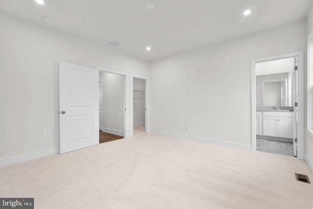 unfurnished bedroom featuring carpet, visible vents, a walk in closet, and recessed lighting