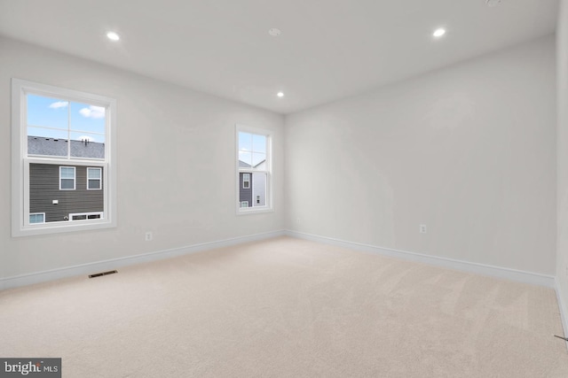 unfurnished room with baseboards, visible vents, light colored carpet, and recessed lighting