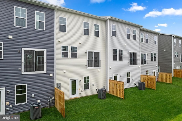 rear view of property with a yard and central air condition unit