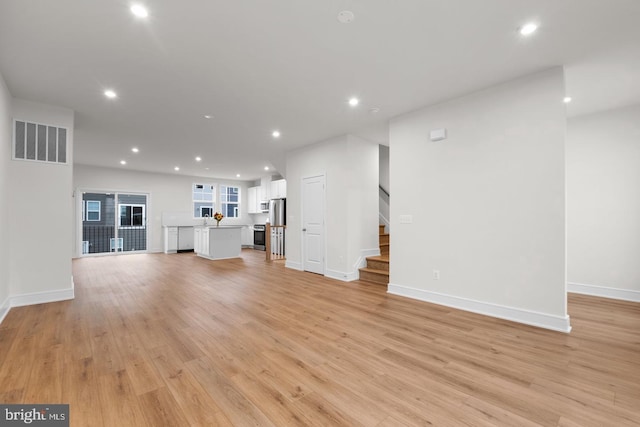 unfurnished living room with light wood finished floors, stairway, visible vents, and recessed lighting