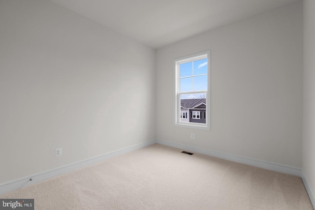 carpeted spare room featuring visible vents and baseboards