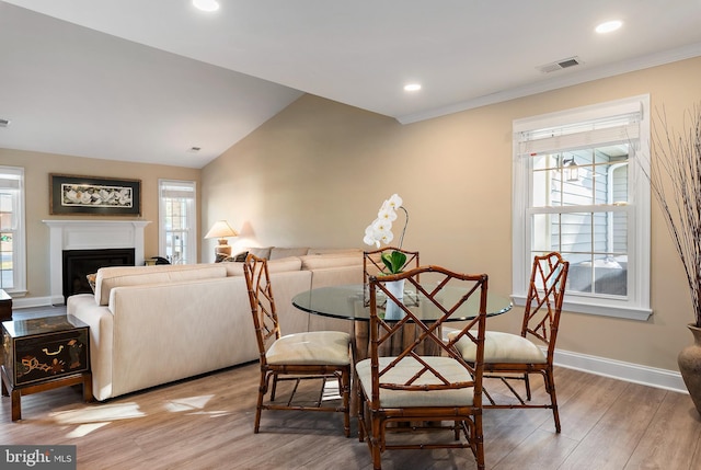 dining area featuring light wood-style floors, baseboards, a fireplace, and visible vents