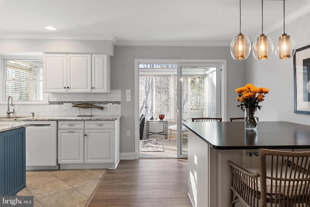 kitchen featuring decorative backsplash, ornamental molding, white dishwasher, white cabinetry, and a sink