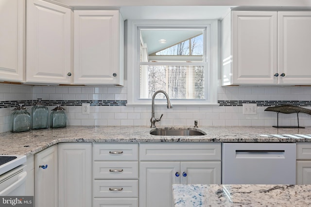 kitchen featuring dishwasher, backsplash, a sink, and white cabinets