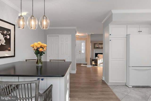 kitchen featuring ornamental molding, dark countertops, freestanding refrigerator, and white cabinets