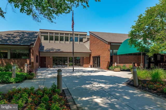 view of front of house featuring brick siding and roof with shingles