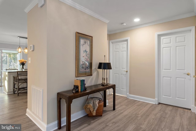 foyer featuring baseboards, light wood-style flooring, visible vents, and crown molding