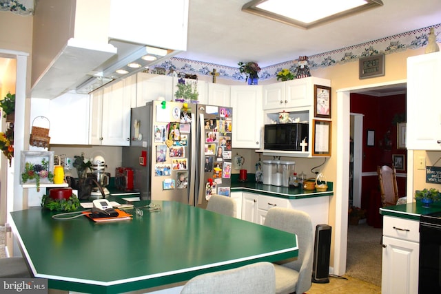 kitchen featuring dark countertops, black microwave, white cabinets, and freestanding refrigerator