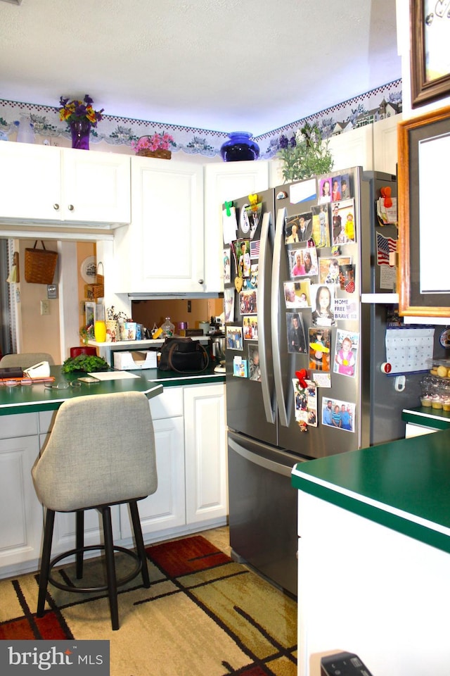 kitchen featuring freestanding refrigerator and white cabinets