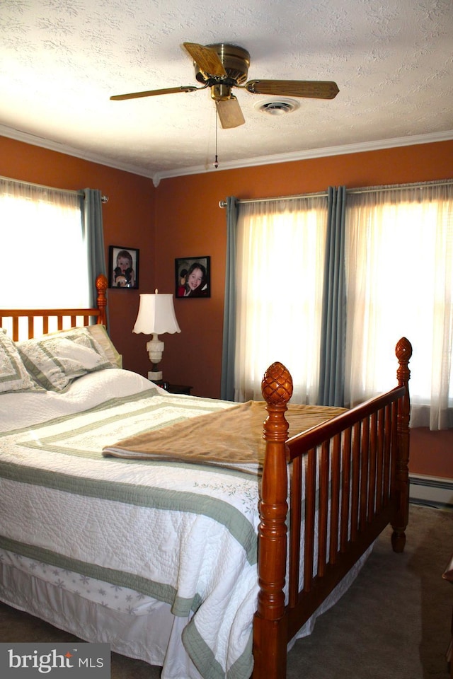 carpeted bedroom with a textured ceiling, ceiling fan, a baseboard heating unit, visible vents, and crown molding